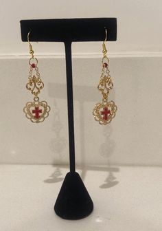 A pair of gold dangle earrings featuring ornate metallic connectors and lace heart charms framing a red enamel cross. Each piece of jewelry in my shop is unique, so if you see something you like, act fast! Enamel Cross, Lace Heart, Cross Earrings, Red Lace, Gold Gold, Gold Earrings Dangle, Heart Charm, Halloween Shopping, Jewelry Earrings Dangle