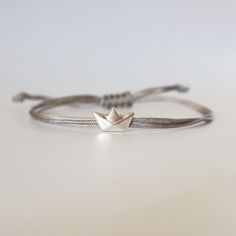 Introducing our exquisite origami paper boat charm bracelet, available in silver plate or 24k gold plate charm. This dainty bracelet tells a story of childhood nostalgia and the beauty of imagination. Each bracelet is crafted, creating a whimsical and unique accessory that is sure to catch attention. The simplistic yet elegant design makes it a versatile piece, suitable for any occasion - from casual outings to special events. Gift this charming bracelet to yourself or a loved one, and let it ca Handmade Sterling Silver Friendship Bracelets, Tiny Adjustable Sterling Silver Bracelets, Handmade White Gold Bracelets As Gift, Nickel-free Silver Friendship Bracelet, Handmade Silver Bracelet For Best Friend, Handmade White Gold Bracelets Gift, Silver Dainty Friendship Bracelets, Sterling Silver Friendship Bracelets As Gift, Minimalist Silver Friendship Bracelets