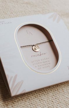 a white box with a silver bracelet in it's packaging on a beige surface