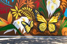 a mural painted on the side of a building with two yellow butterflies flying over it