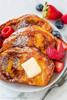 french toast with butter and berries on a white plate