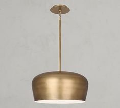 a brass colored pendant light hanging from a ceiling fixture with a white wall in the background