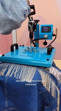 a person using a sewing machine to sew jeans on the back of a denim jacket