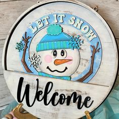 a sign that says let it snow, welcome with a snowman in the center