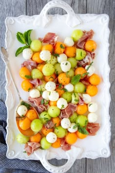 a white plate topped with oranges and mozzarella covered in green garnish