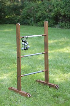 a wooden rack with several baseballs hanging from it's sides in the grass