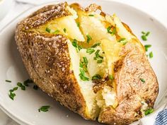 a baked potato on a white plate with parsley sprinkled around the edges