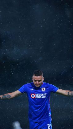 a soccer player is standing in the rain with his arms spread out and hands outstretched