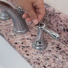 a person's hand is on the handle of a faucet