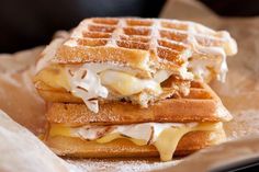 two waffle sandwiches with melted cheese and syrup on them are sitting on wax paper