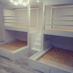 two white bunk beds in a room with wood flooring and lights on the ceiling