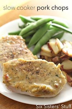 a white plate topped with meat, potatoes and green beans on top of a wooden table