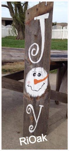 a wooden sign with the letter j painted on it's side and an image of a snowman