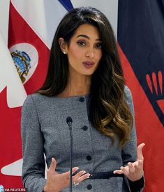 a woman giving a speech in front of flags