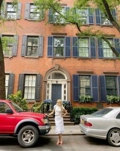 a woman standing in front of a red truck parked next to a tall brick building