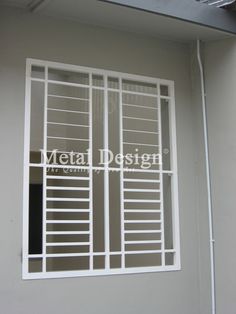 a window with bars on the side of it in front of a gray wall and ceiling fan