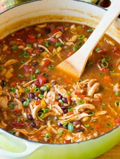 a green pot filled with chicken tortilla soup on top of a wooden table