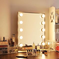 a vanity mirror with lights on it in a room next to a desk and drawers