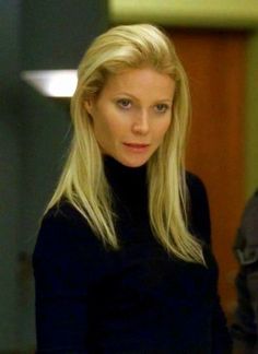 a woman with long blonde hair wearing a black turtle neck sweater and jeans looking at the camera