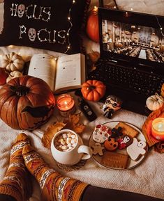 an open laptop computer sitting on top of a bed next to halloween decorations and cookies