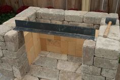 an outdoor fireplace made out of cinder blocks and bricks with a bench on the side