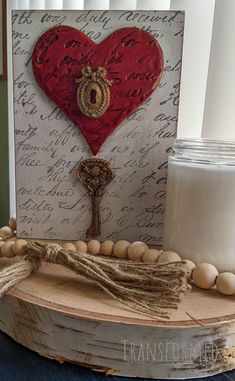 a wooden table topped with a candle and a heart shaped key on top of it