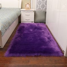 a bedroom with a purple rug on the floor next to a white dresser and bed