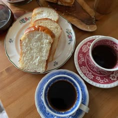 two plates with slices of bread on them next to cups of coffee