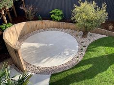 a circular garden area in the middle of a yard with green grass and small trees