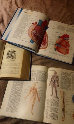 an open book with pictures of human body and heart on it sitting on a bed