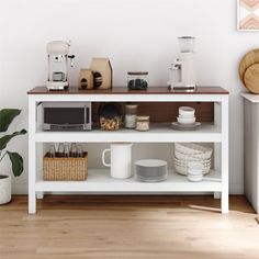 a white shelf with plates, cups and coffee mugs on it next to a potted plant