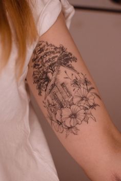 a woman's arm with flowers and a house tattoo on the left side of her arm