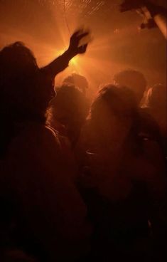 a group of people standing around each other in a room with lights on the ceiling