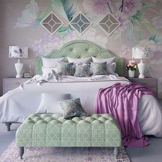 a large bed sitting next to a wall with flowers on the walls and pillows in front of it