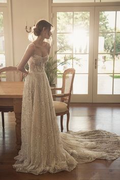 a woman standing in front of a table wearing a wedding dress