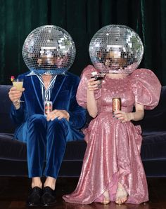 two people sitting on a couch with disco balls over their heads and drinks in front of them