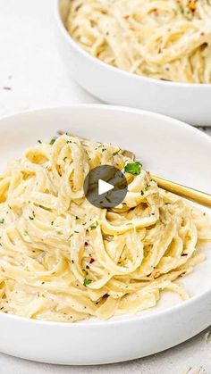 two white bowls filled with pasta and topped with parsley sprinkled on top