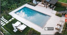 an aerial view of a backyard with a pool and lounge chairs in the foreground