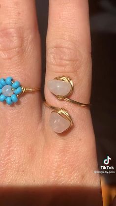 a woman's hand with two rings on it and one ring has blue beads