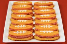 a white plate topped with cookies covered in orange frosting and football cutouts on top of each other