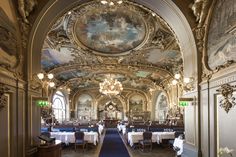 an ornately decorated dining room with blue carpet and white tablecloths on the tables