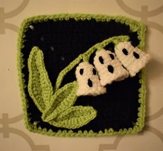 a crocheted square with three black and white flowers on it, in the shape of ghost eyes