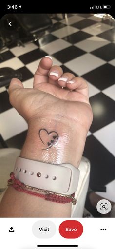 a woman's wrist with a heart tattoo on it