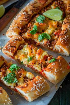 several slices of pizza sitting on top of a cutting board next to lime wedges