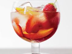 a glass filled with fruit and ice on top of a table