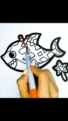 someone is drawing a fish on the paper with marker and pen, while it's in color