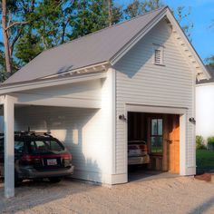 a car is parked in front of a white garage with a carport and two cars