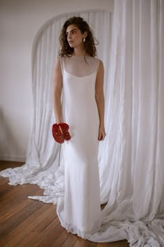 a woman in a white dress holding a red flower