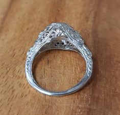 an ornate silver ring sitting on top of a wooden table