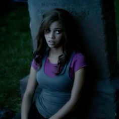 a young woman sitting in front of a grave